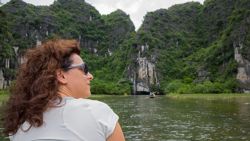 Mujer navegando en río rodeado de montañas verdes  